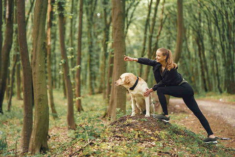 A woman and her dog exercising amidst trees