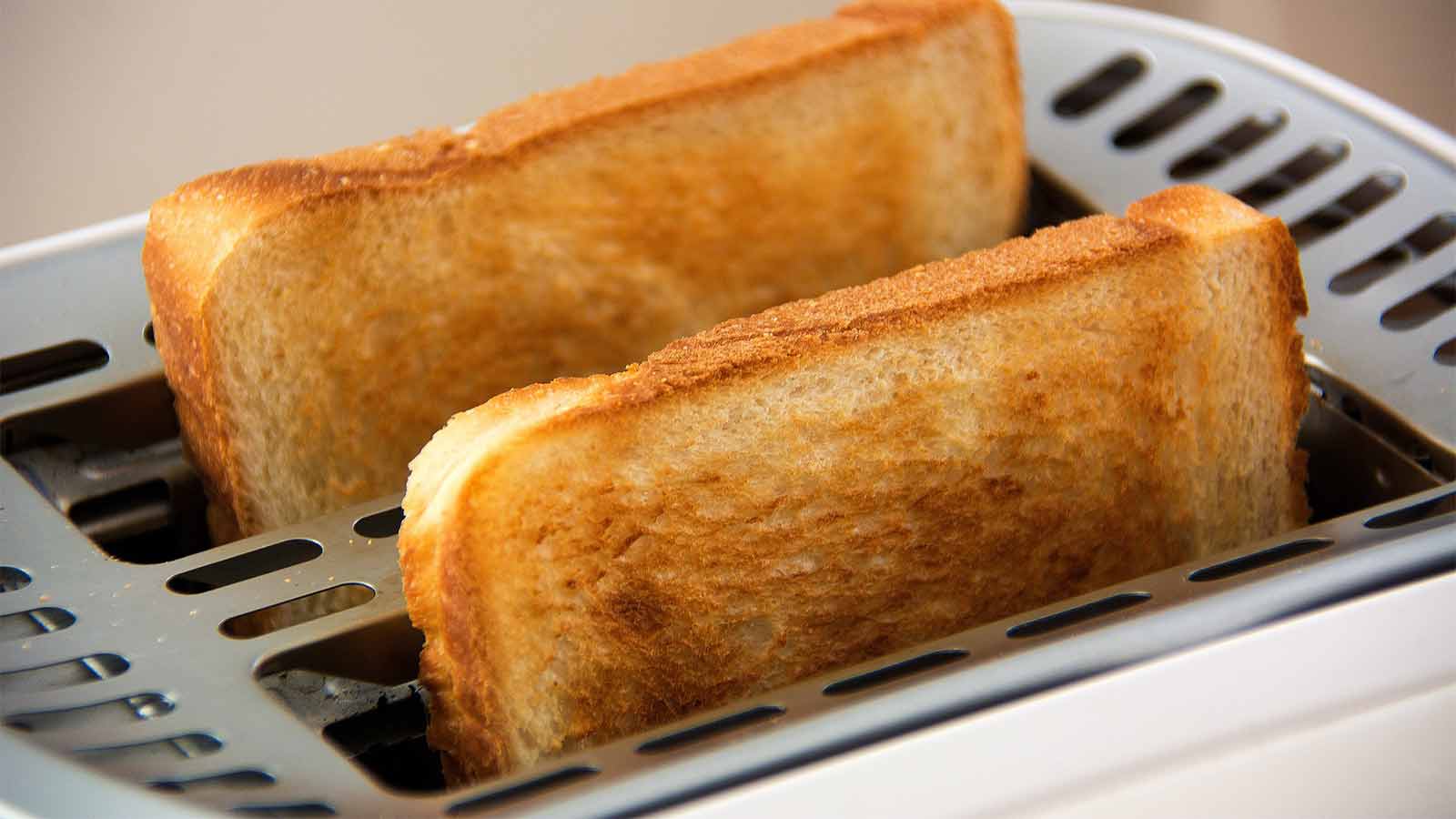 Un Grille-pain Blanc Et Argent Sur Un Mur Gris Sur Une Table En Bois Blanc  Avec Des Morceaux De Pain Qui Sort