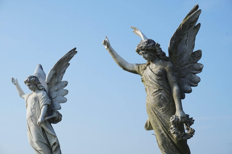 Two angel statues pointing at the blue sky