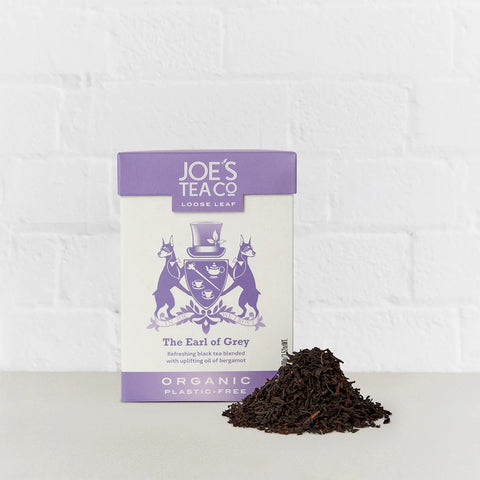 JOE'S TEA - ORGANIC THE EARL OF GREY Image. The box is sitting on a grey table, with a pile of loose leaf teat next to it.