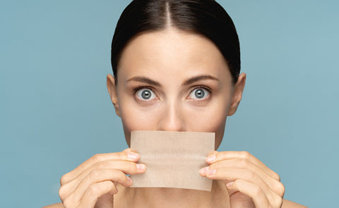 Woman Using Blotting Paper On Face