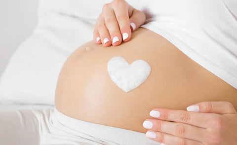 Woman Applying Lotion On Preganant Belly