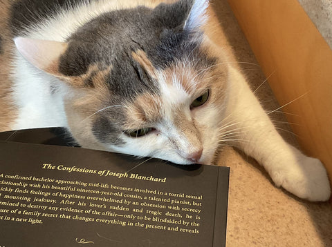 Cassidy the Cat lying on top of a copy of The Confessions of Joseph Blanchard