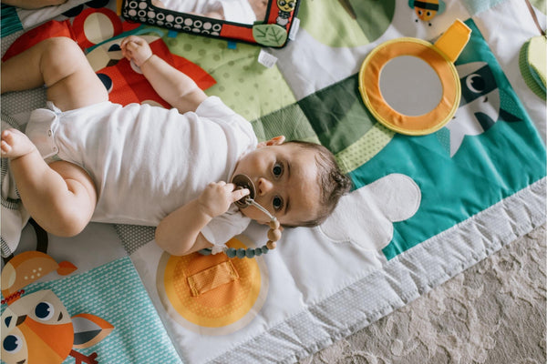 camera-looks-down-to-a-baby-laying-in-a-colorful-mat