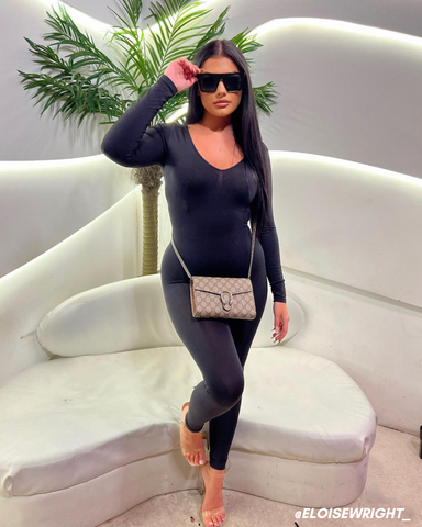 Female influencer in black jumpsuit and heels