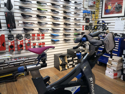 A bike for fitting sits in a bike shop against a cycling shoe wall.