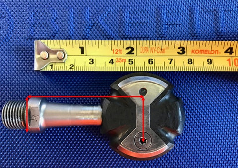 Road bike pedal laid flat against a measuring tape