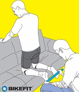 A digital illustrative of a cyclist kneeling on a couch while his feet are being measured