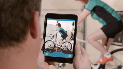 A cyclist being analyzed by a bike fitter on an ipad