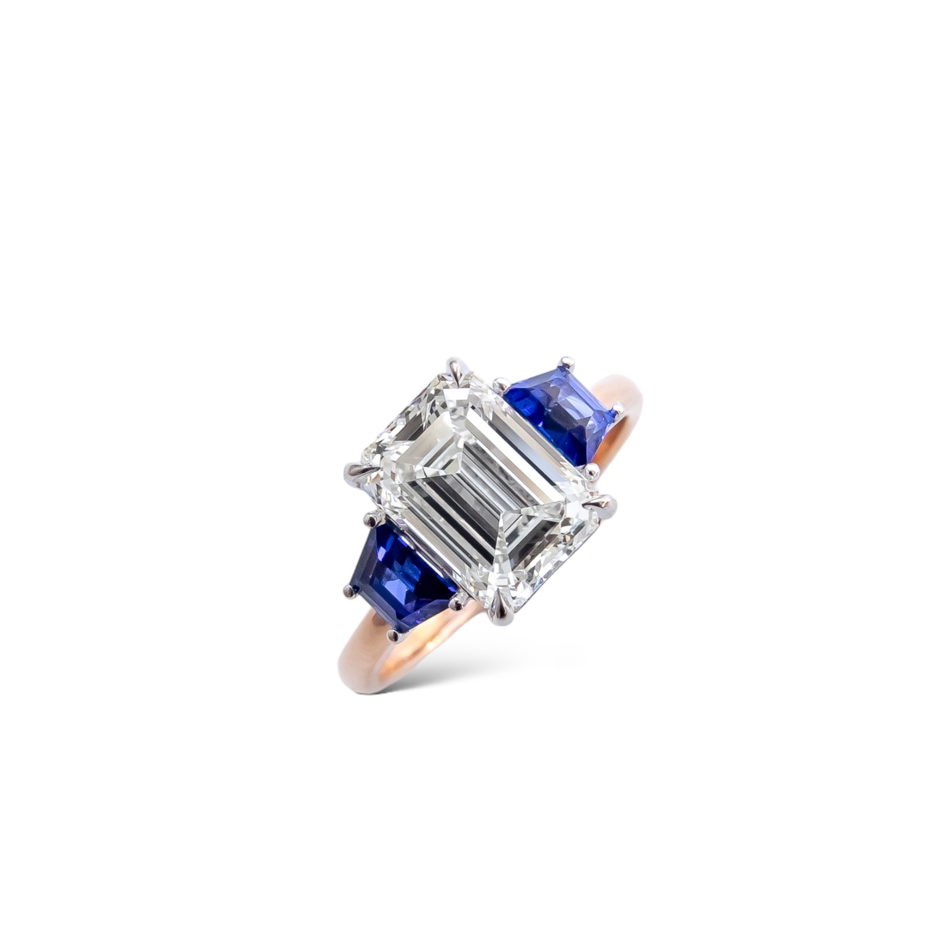 Emerald cut diamond engagement ring with blue sapphire side stones in rose golf