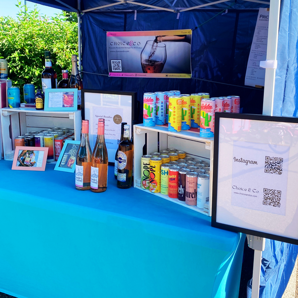 Table with blue table cloth and nonalcoholic beverages on top. Outdoor farmers market booth