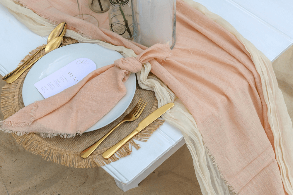boho wedding table setup on the beach with peach toned elements