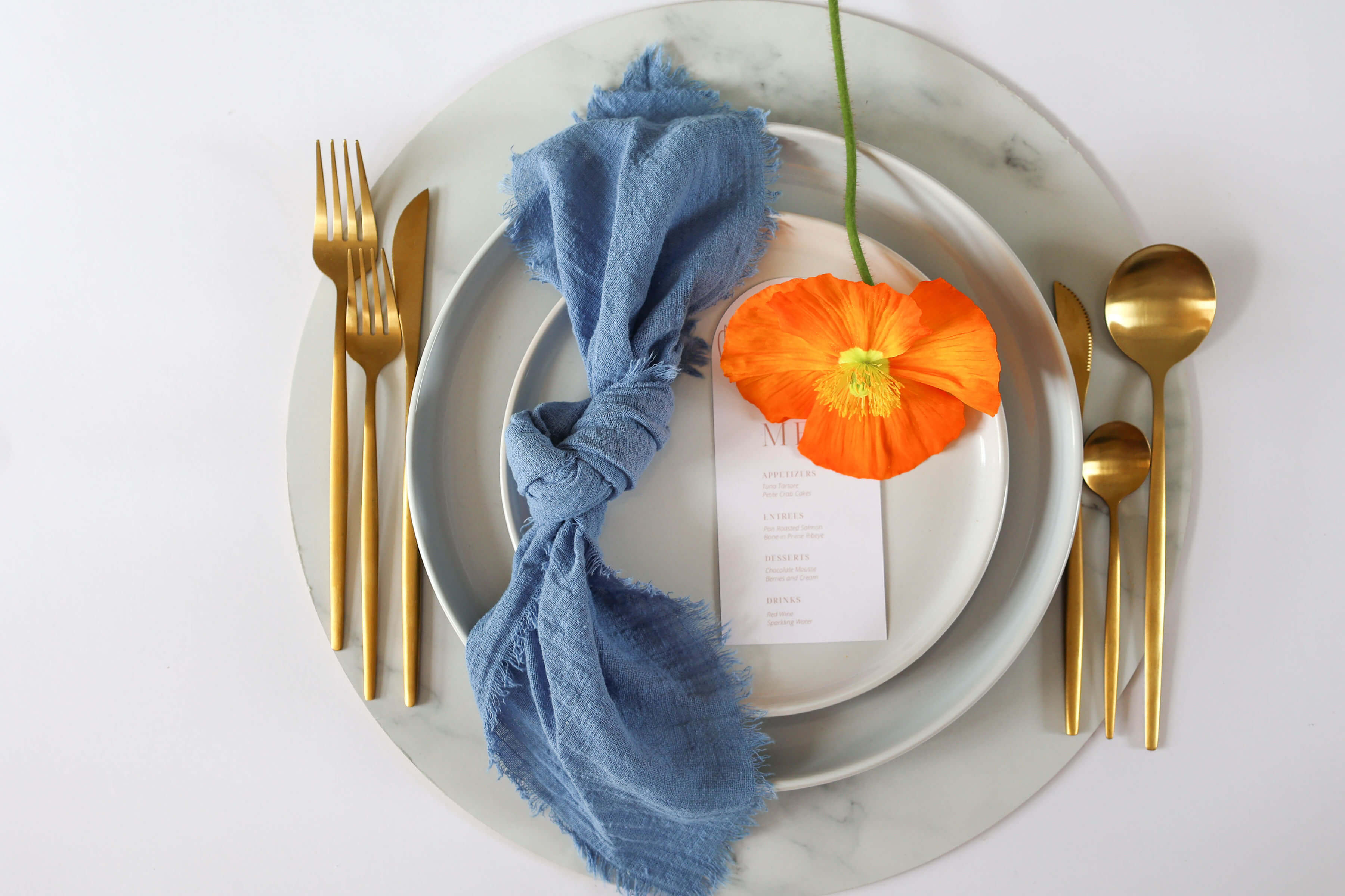 French blue napkin on ceramic plate set up with wedding cutlery