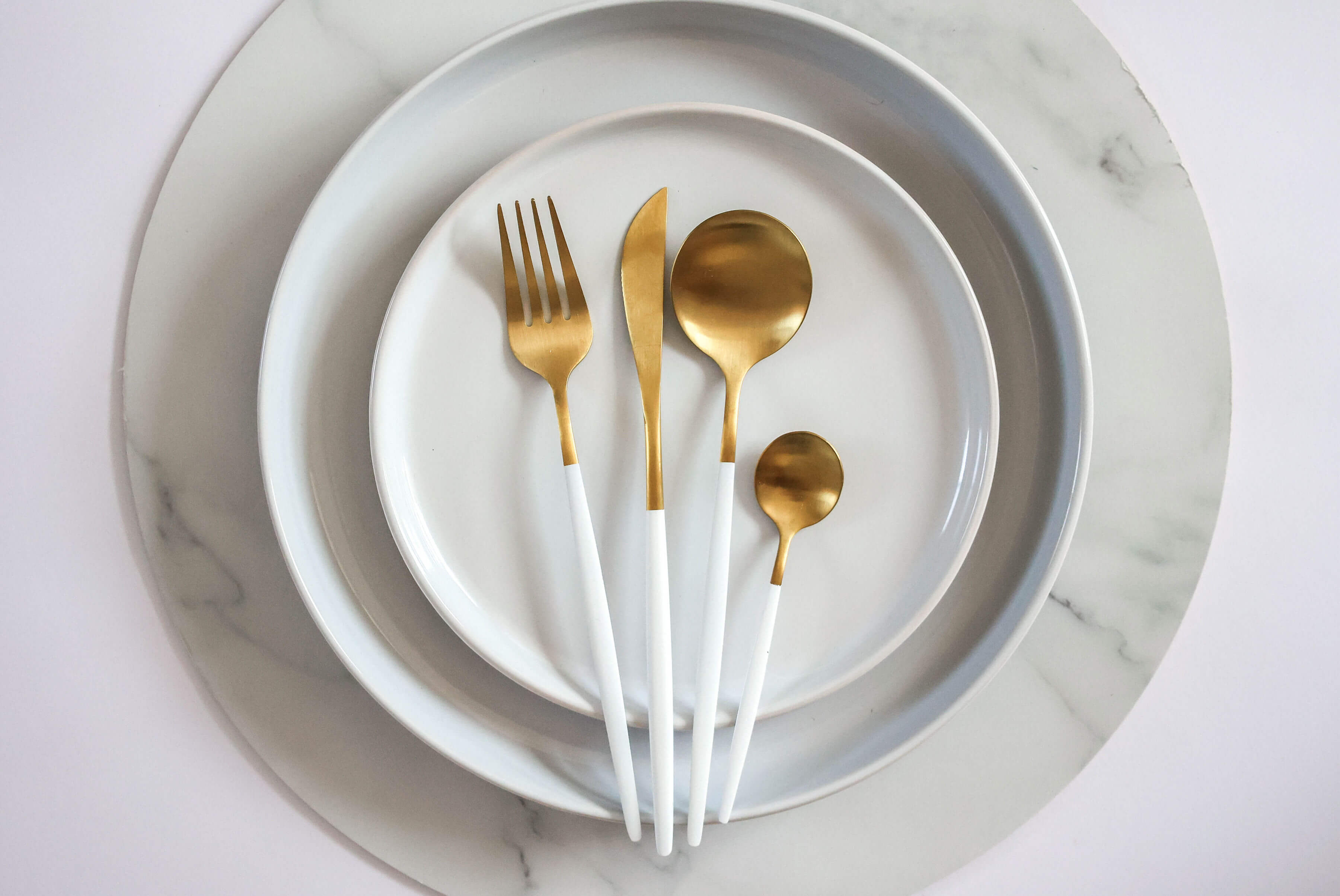 White drip set cutlery on top of ceramic plates
