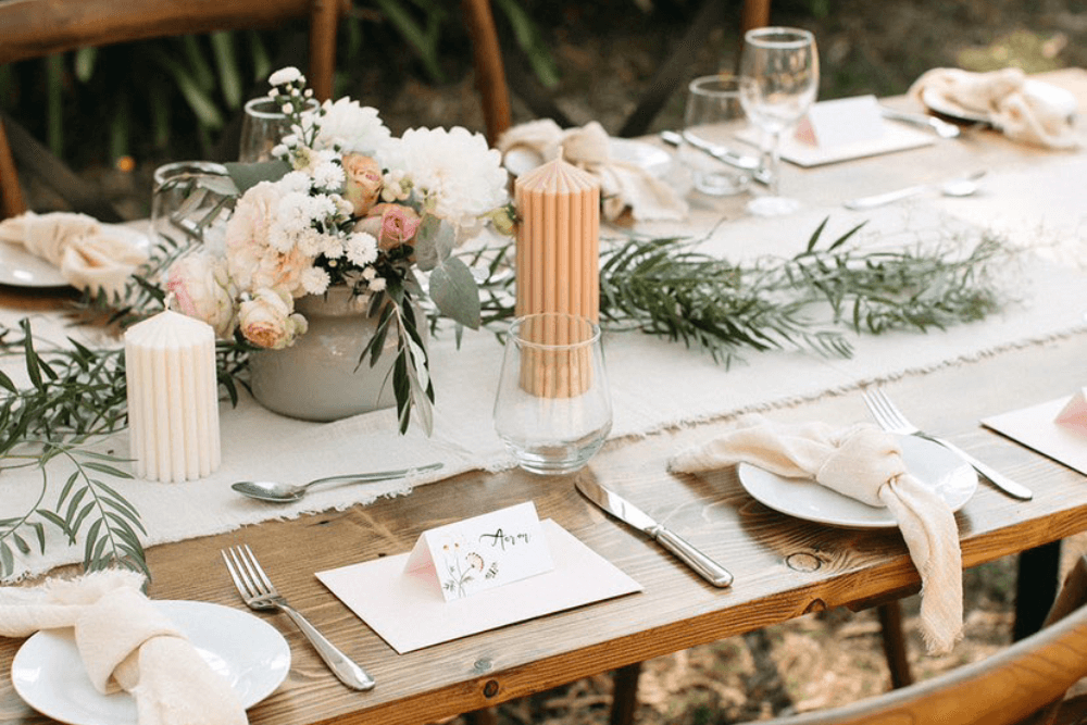 event table set up with personalised name cards, candles, and florals