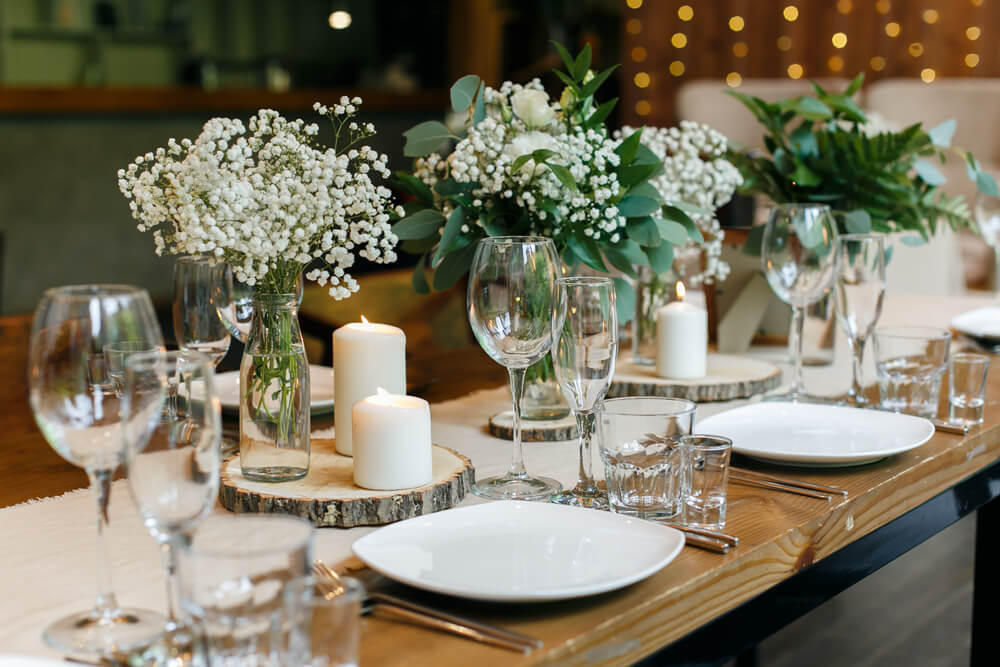 rustic wedding table setup with small and tall candles and flower vases