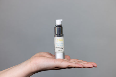 Ethos Skincare Restorative Eye Serum being held up by a woman’s hand.