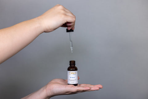 Ethos Skincare Rx Serum resting on a woman’s palm as the dropper is lifted out of the bottle.