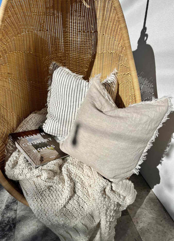 Outdoor rattan chair styled with 100% European flax linen cushions from Lurline Co.