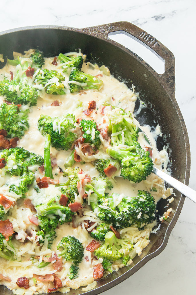 cooked bacon and broccoli in cast iron skillet with creamy garlic sauce