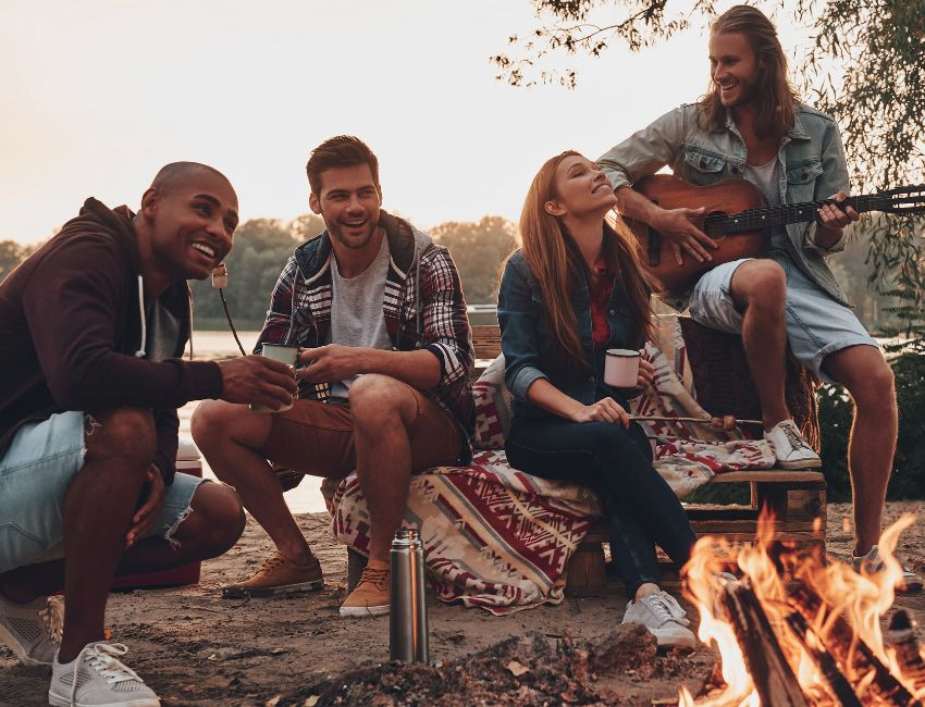 Friends sit together next to the campfire