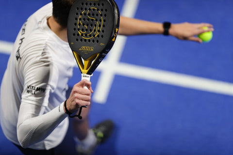 Close-up of a player serving during a game of padel-tennis.