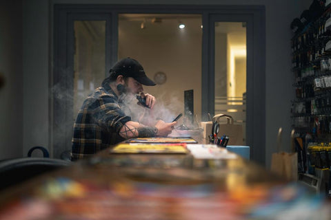 Man vaping at counter inside e-cigarette store