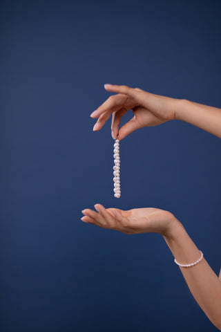 Deux mains tenant un bracelet de perles