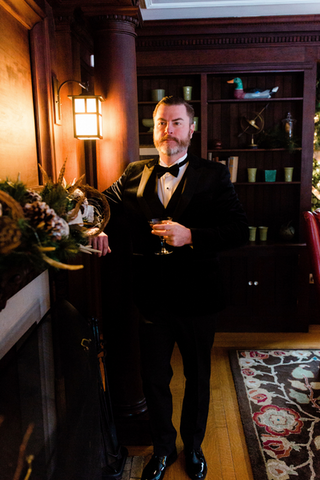 Groom standing at fireplace, with bourbon cocktail in library at Willowdale Estate, Boston, Massachusetts