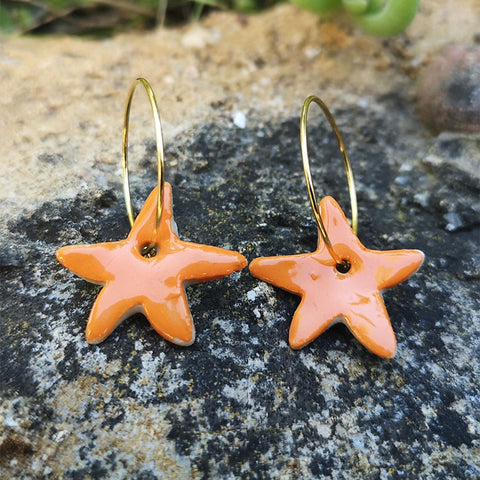 Boucles d'oreilles orange étoile pour femme et ado pendante sur un rocher