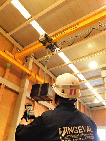 Inner view of the Factory worker operating the Overhead Bridge crane and hoist lifting the bulk goods