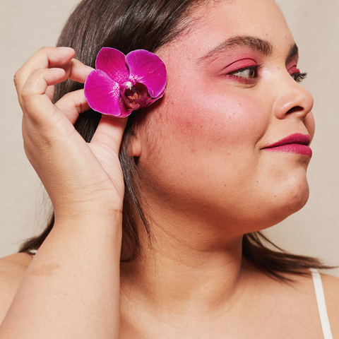 woman with flower in her hair and pink make up, smiling