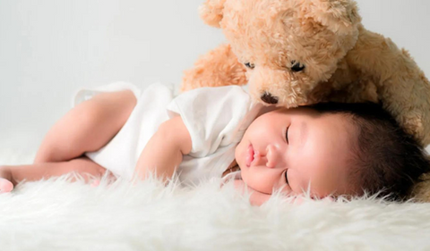 Bébé qui dort avec son ours en peluche