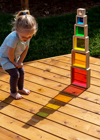 Young girl playing with Rainbow Stacking Pyramid outdoors