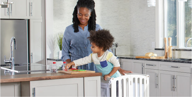 Imagen de un niño pequeño y su madre usando el taburete auxiliar de cocina Guidecraft para hornear juntos en la cocina