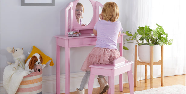 Imagen de una niña usando el juego de tocador y taburete para niños en rosa para jugar a fingir