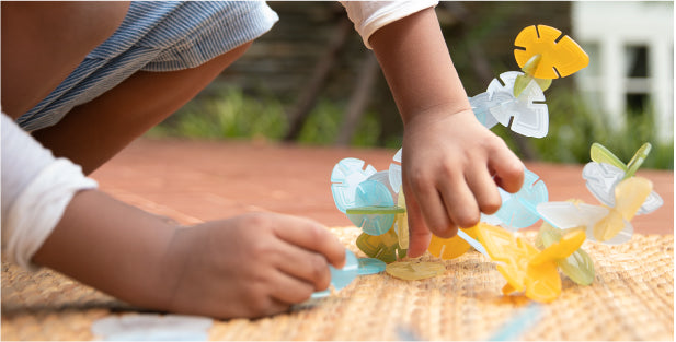 Image of child's hands playing with nature-based building toy Interlox Leaves