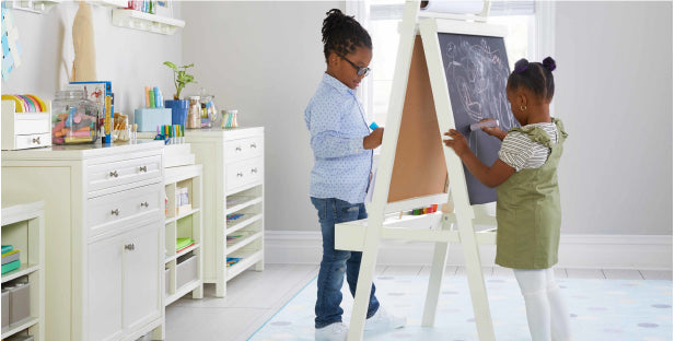 Image of two young children using the double-sided easel from the Martha Stewart Crafting Kids Furniture Collection.