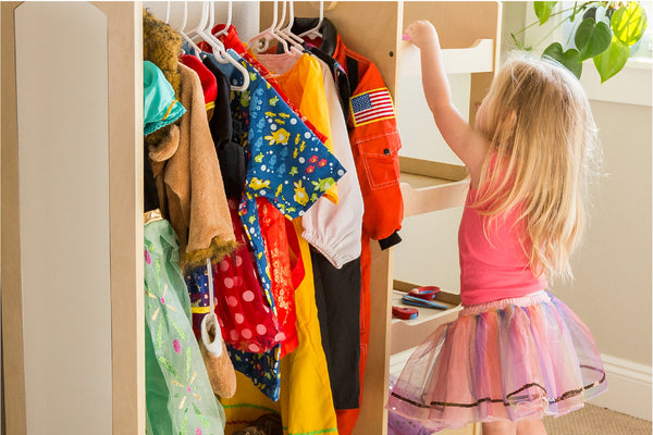 Image of a young girl using a Guidecraft dress up center to store and organize her pretend play costumes and accessories.