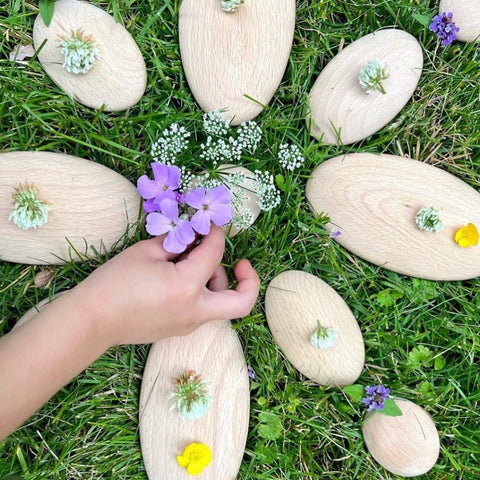 Children incorporating found loose parts into outdoor play using Guidecraft's Wood Stackers River Stones