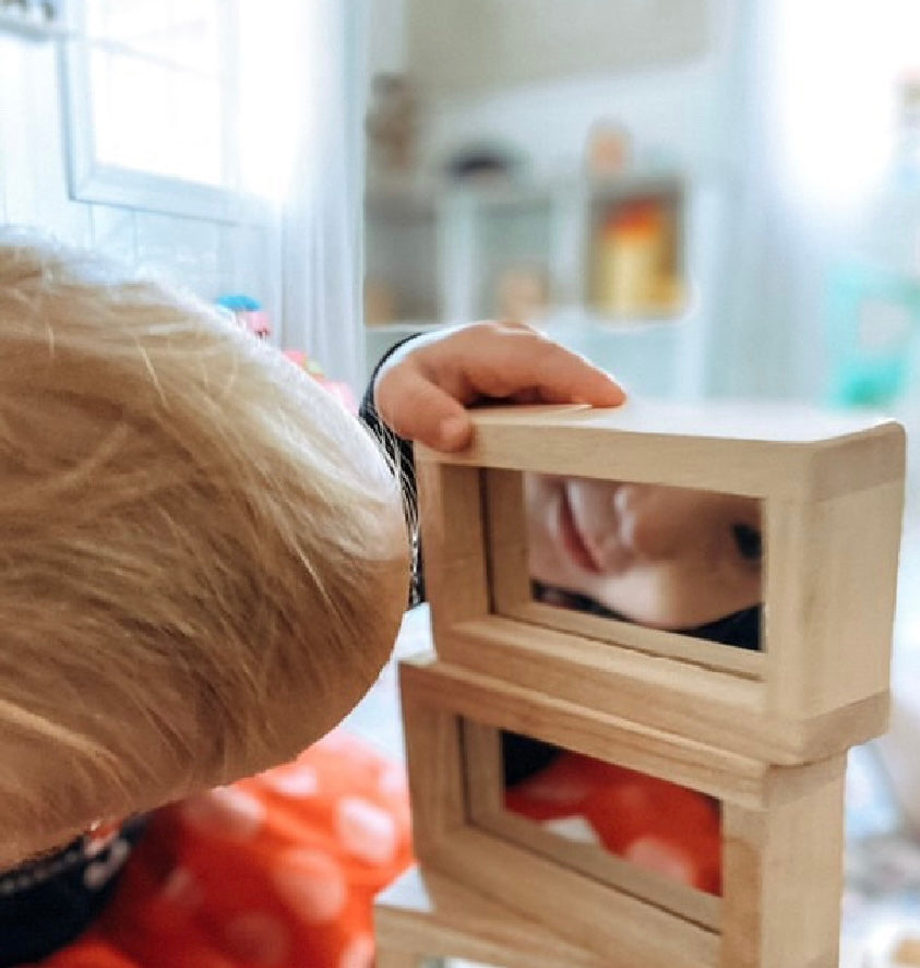 Child looking at her reflection in Guidecraft Mirror Blocks