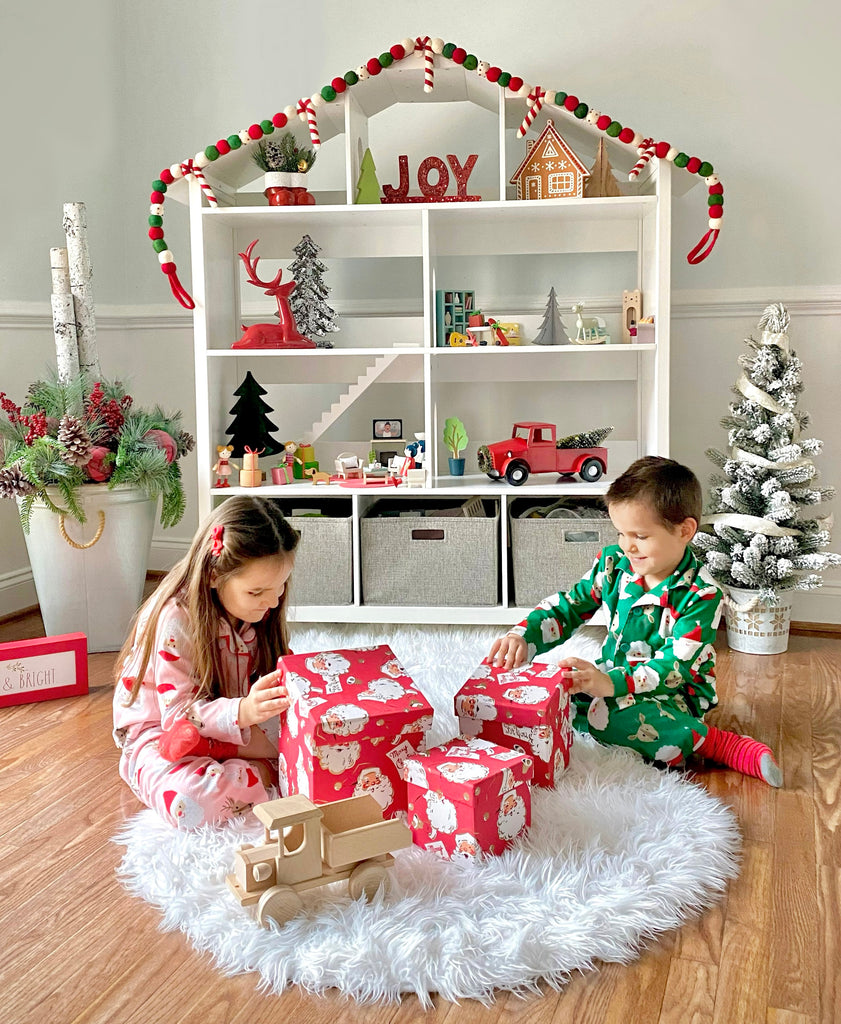 Sister and brother opening Christmas presents in front of Martha Stewart White Dollhouse Bookcase