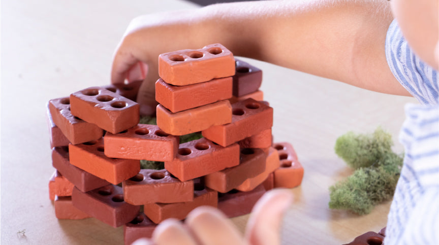 jeune garçon jouant avec Guidecraft Little Bricks, un jouet de construction naturel qui constitue le cadeau de vacances idéal pour les enfants de 3 ans et plus