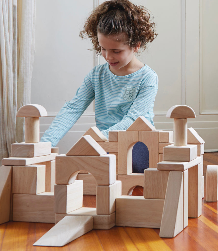 Image of a young girl building using Guidecraft wooden Unit Blocks.