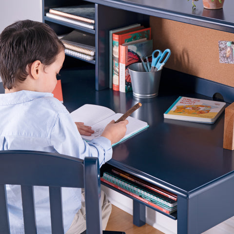 Young boy writing at the Taiga navy kids' desk