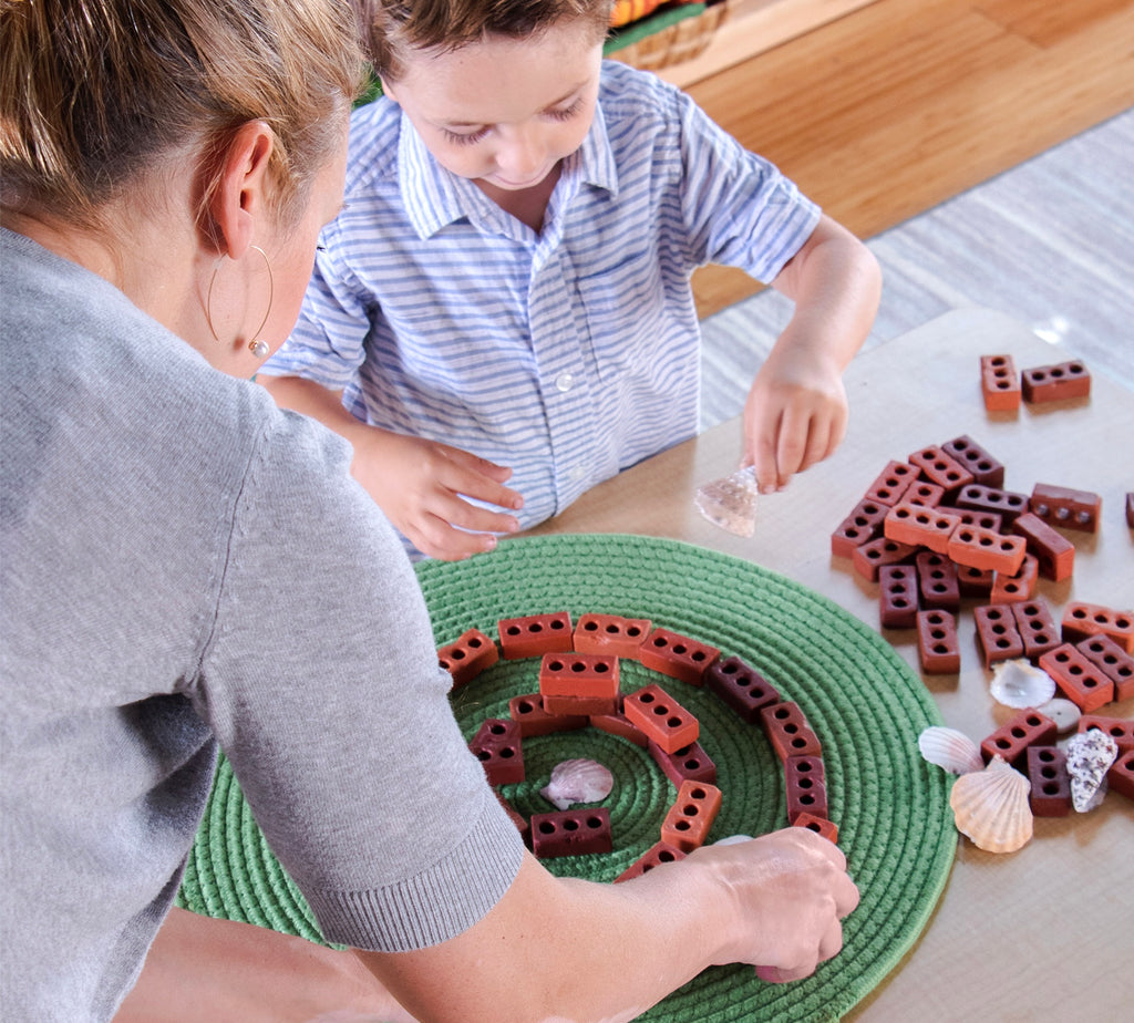 Mother and son building with Little Bricks on green mat on table
