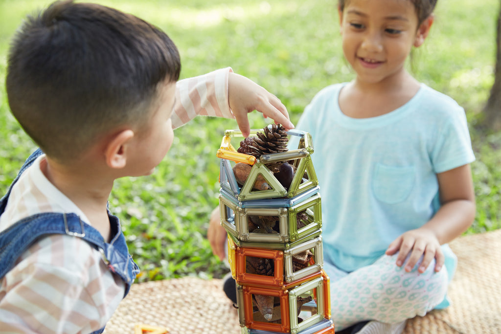 Boy and girl placing pine cones into Power Clix built tower