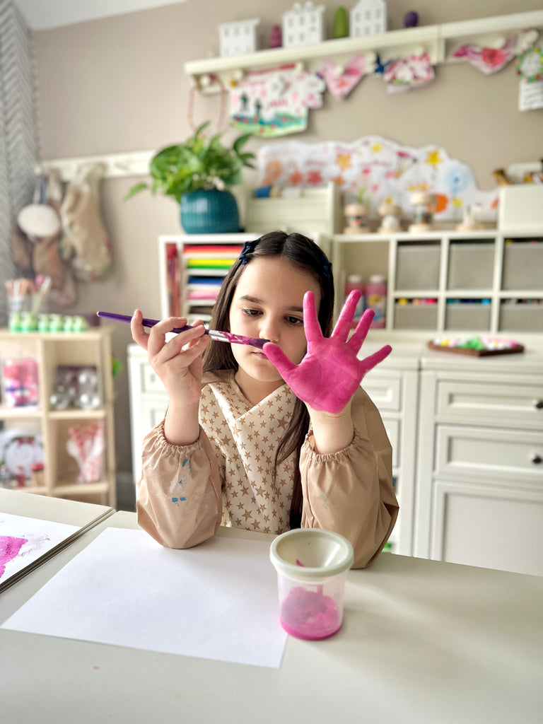 Girl painting her hand at Martha Stewart Crafting Kids' Art Table