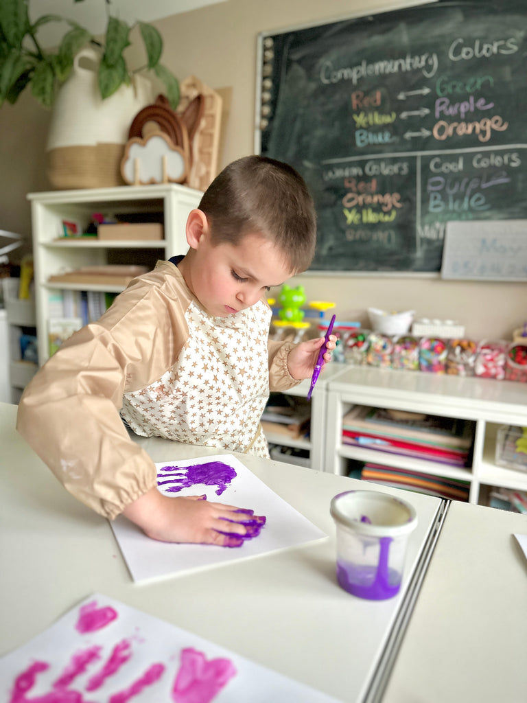 Boy making handprint at Martha Stewart Crafting Kids' Art Table