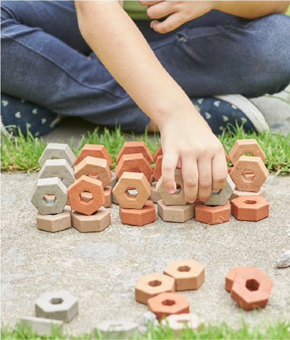young child playing with Guidecraft Little Pavers, a natural building toy for children 4 and up. This is an educational toy that makes the perfect holiday gift for kids